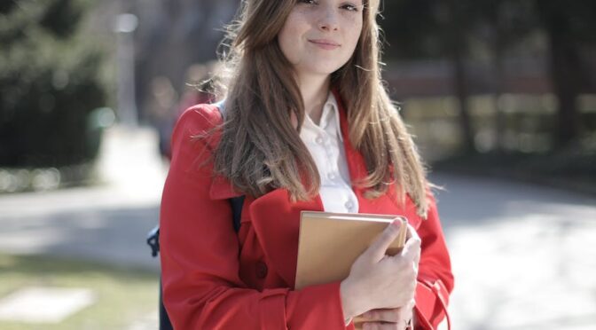 woman in red coat holding brown book